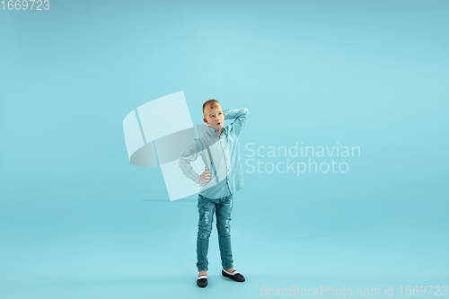 Image of Childhood and dream about big and famous future. Pretty little boy isolated on blue background