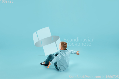 Image of Childhood and dream about big and famous future. Pretty little boy isolated on blue background