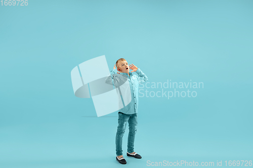 Image of Childhood and dream about big and famous future. Pretty little boy isolated on blue background
