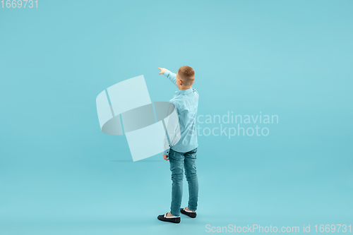 Image of Childhood and dream about big and famous future. Pretty little boy isolated on blue background