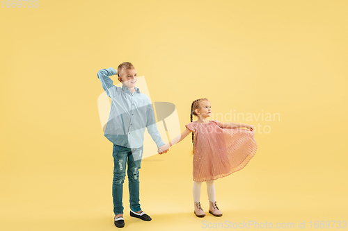 Image of Childhood and dream about big and famous future. Boy and girl isolated on yellow studio background