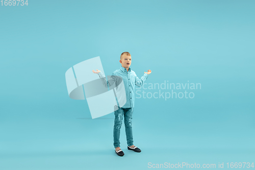 Image of Childhood and dream about big and famous future. Pretty little boy isolated on blue background