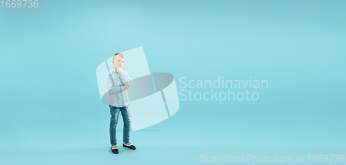 Image of Childhood and dream about big and famous future. Pretty little boy isolated on blue background