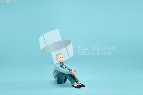 Image of Childhood and dream about big and famous future. Pretty little boy isolated on blue background