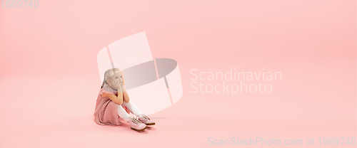 Image of Childhood and dream about big and famous future. Pretty longhair girl isolated on coral pink background