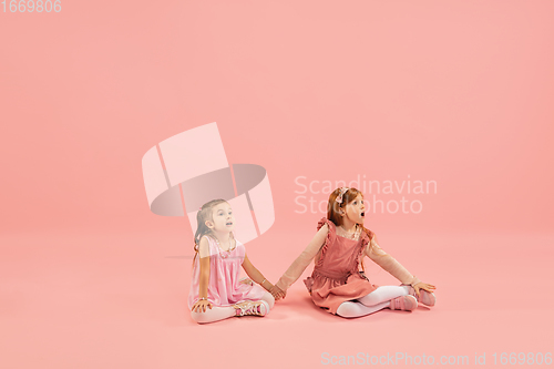 Image of Childhood and dream about big and famous future. Pretty little girls isolated on coral pink background