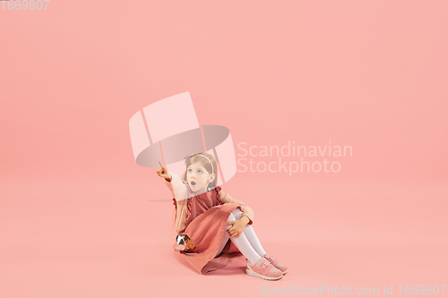 Image of Childhood and dream about big and famous future. Pretty longhair girl isolated on coral pink background