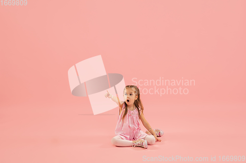 Image of Childhood and dream about big and famous future. Pretty longhair girl isolated on coral pink background