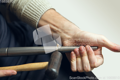 Image of Close up hands of jeweller, goldsmiths making of golden ring with gemstone using professional tools.