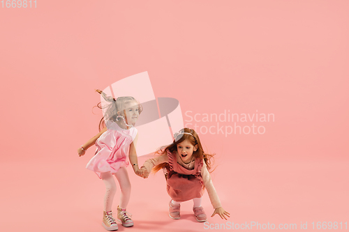 Image of Childhood and dream about big and famous future. Pretty little girls isolated on coral pink background