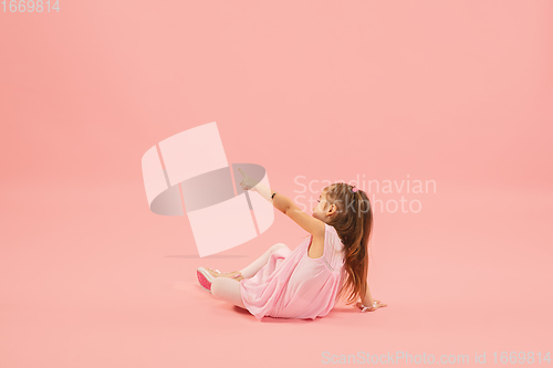 Image of Childhood and dream about big and famous future. Pretty longhair girl isolated on coral pink background