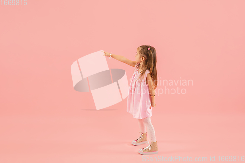 Image of Childhood and dream about big and famous future. Pretty longhair girl isolated on coral pink background