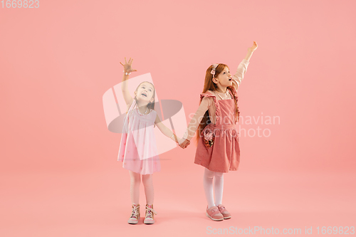 Image of Childhood and dream about big and famous future. Pretty little girls isolated on coral pink background