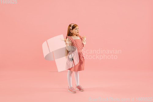 Image of Childhood and dream about big and famous future. Pretty longhair girl isolated on coral pink background