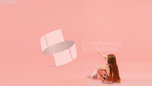 Image of Childhood and dream about big and famous future. Pretty longhair girl isolated on coral pink background