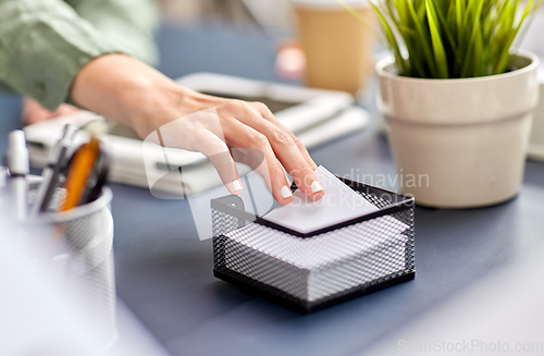 Image of businesswoman taking note paper at office