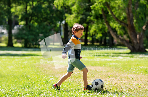 Image of happy little boy with ball playing soccer at park