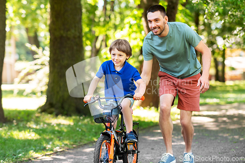 Image of father teaching little son to ride bicycle at park