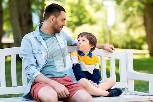 Image of father with son sitting on park bench and talking