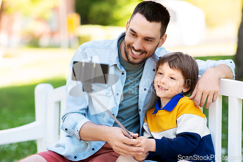 Image of father and son taking selfie with phone at park