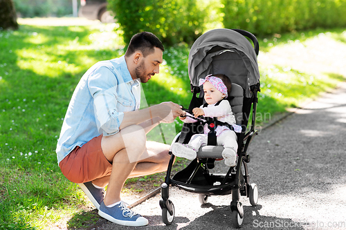 Image of happy father with child in stroller at summer park