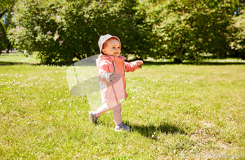 Image of happy little baby girl walking at park in summer