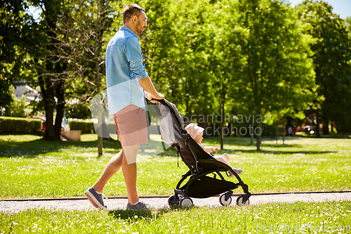 Image of happy father with child in stroller at summer park