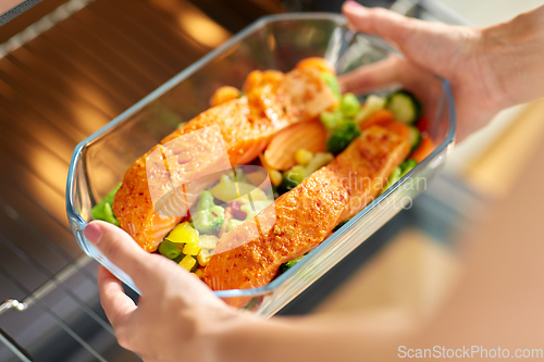 Image of woman cooking food in oven at home kitchen