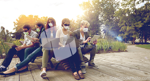 Image of teenage students in masks with computers at campus