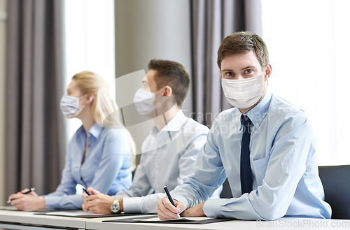 Image of group of businesspeople in masks meeting at office
