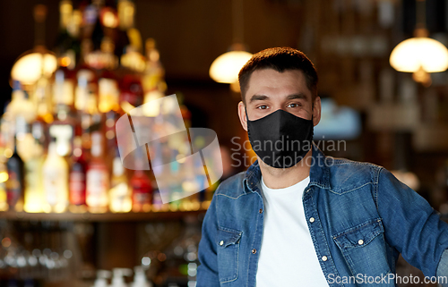 Image of young man in black reusable mask at bar or pub