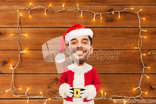 Image of happy santa over garland on wooden background