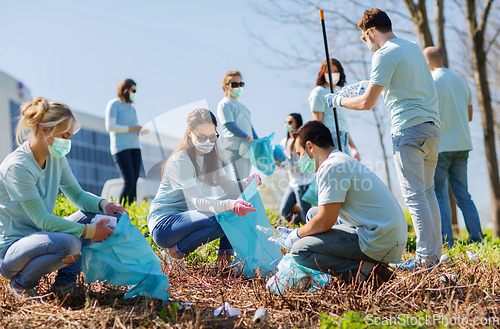 Image of volunteers in masks with bags cleaning outdoors