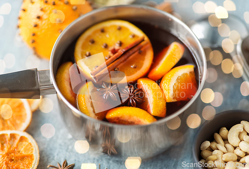 Image of pot with hot mulled wine, orange slices and spices