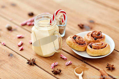 Image of eggnog with candy cane in mug and cinnamon buns