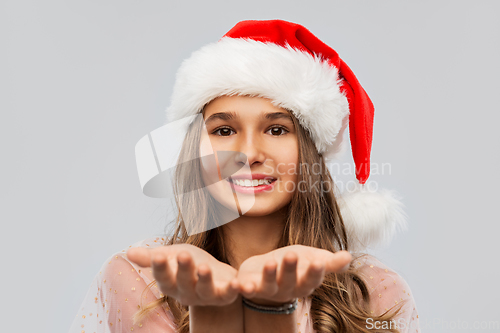 Image of happy teenage girl in santa hat holding something