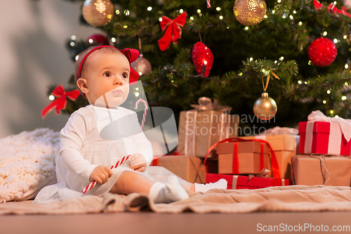 Image of baby girl at christmas tree with gifts at home