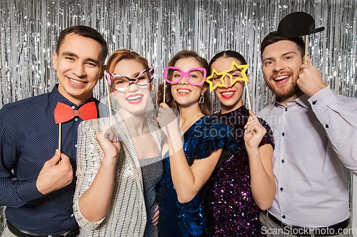 Image of happy friends posing with party props