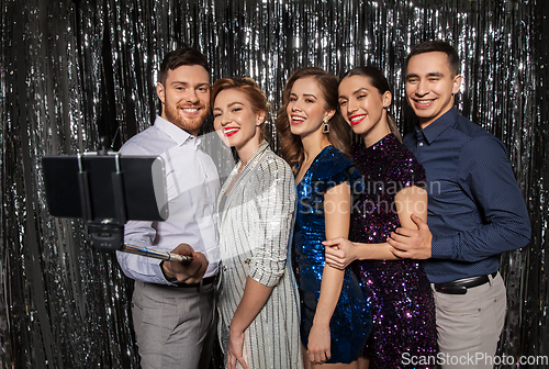 Image of happy friends taking selfie by smartphone at party