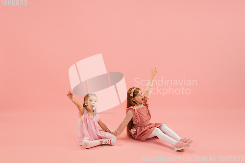 Image of Childhood and dream about big and famous future. Pretty little girls isolated on coral pink background