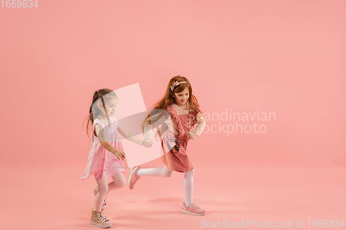 Image of Childhood and dream about big and famous future. Pretty little girls isolated on coral pink background