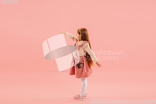 Image of Childhood and dream about big and famous future. Pretty longhair girl isolated on coral pink background