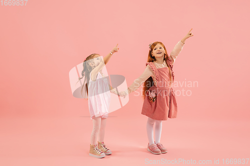 Image of Childhood and dream about big and famous future. Pretty little girls isolated on coral pink background