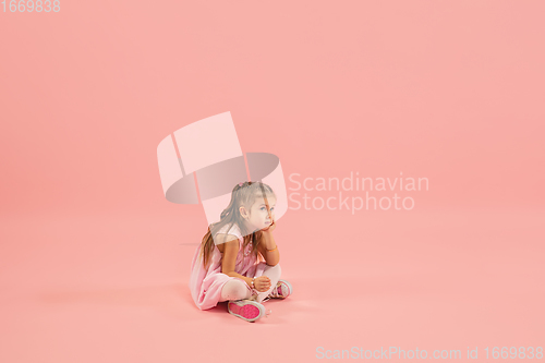 Image of Childhood and dream about big and famous future. Pretty longhair girl isolated on coral pink background