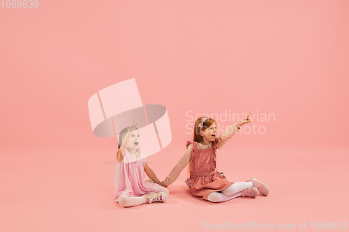 Image of Childhood and dream about big and famous future. Pretty little girls isolated on coral pink background