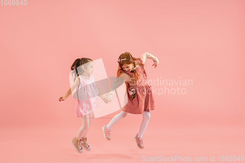 Image of Childhood and dream about big and famous future. Pretty little girls isolated on coral pink background