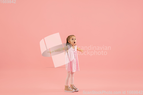 Image of Childhood and dream about big and famous future. Pretty longhair girl isolated on coral pink background