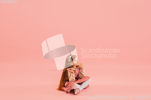 Image of Childhood and dream about big and famous future. Pretty longhair girl isolated on coral pink background