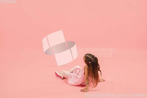 Image of Childhood and dream about big and famous future. Pretty longhair girl isolated on coral pink background