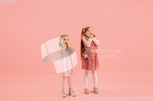 Image of Childhood and dream about big and famous future. Pretty little girls isolated on coral pink background